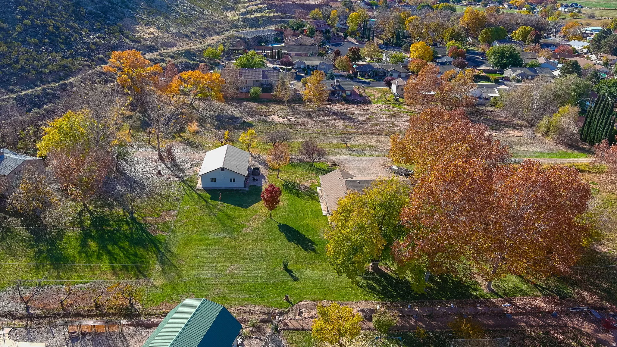 Expansive property featuring a gabled roof residence, substantial green lawn, and mature trees with vibrant autumn foliage