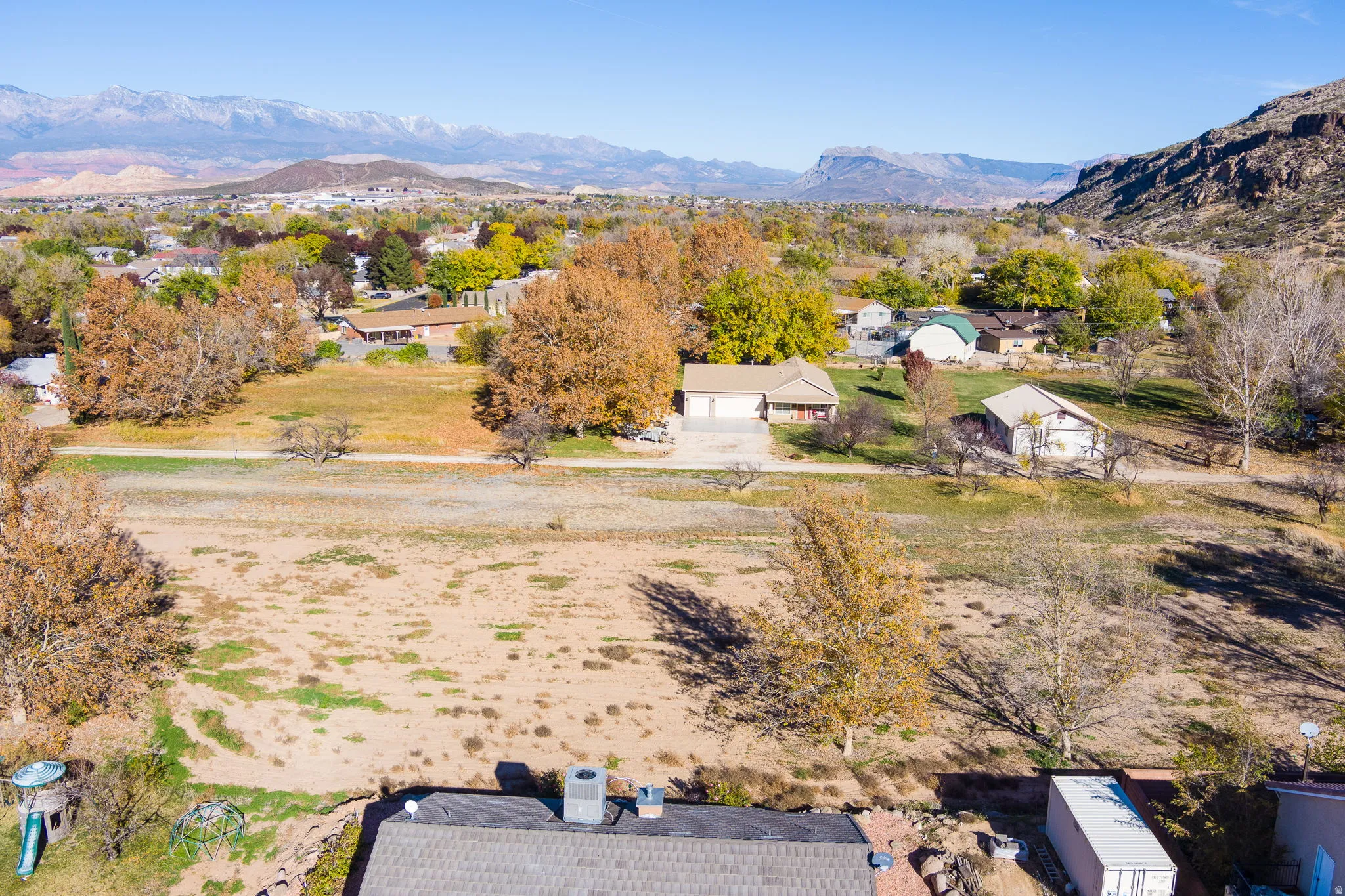 Expansive lot featuring a two-car garage, surrounding mature trees, and a mountain backdrop