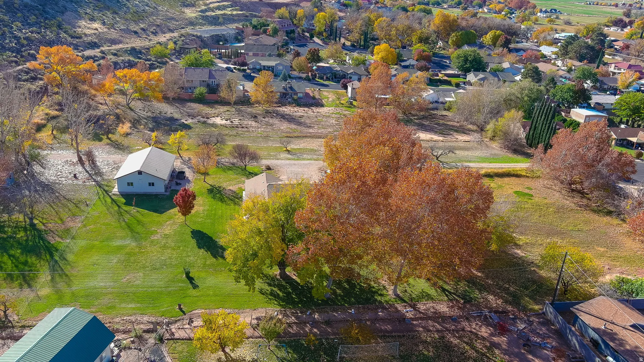 Expansive property featuring a single-story residence with a light-colored exterior and a gabled roof