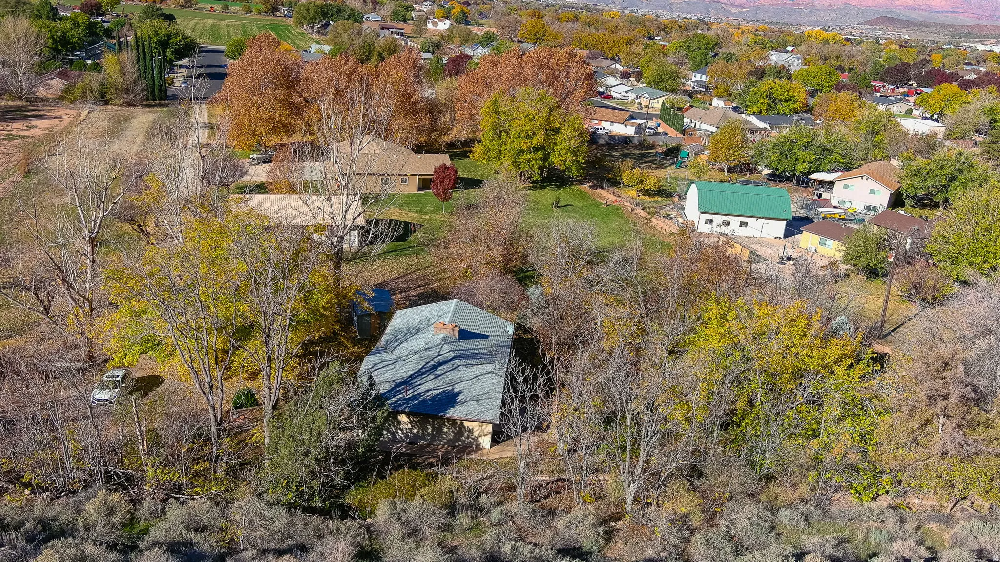Aerial property view showcasing a residential setting with established trees and surrounding landscape