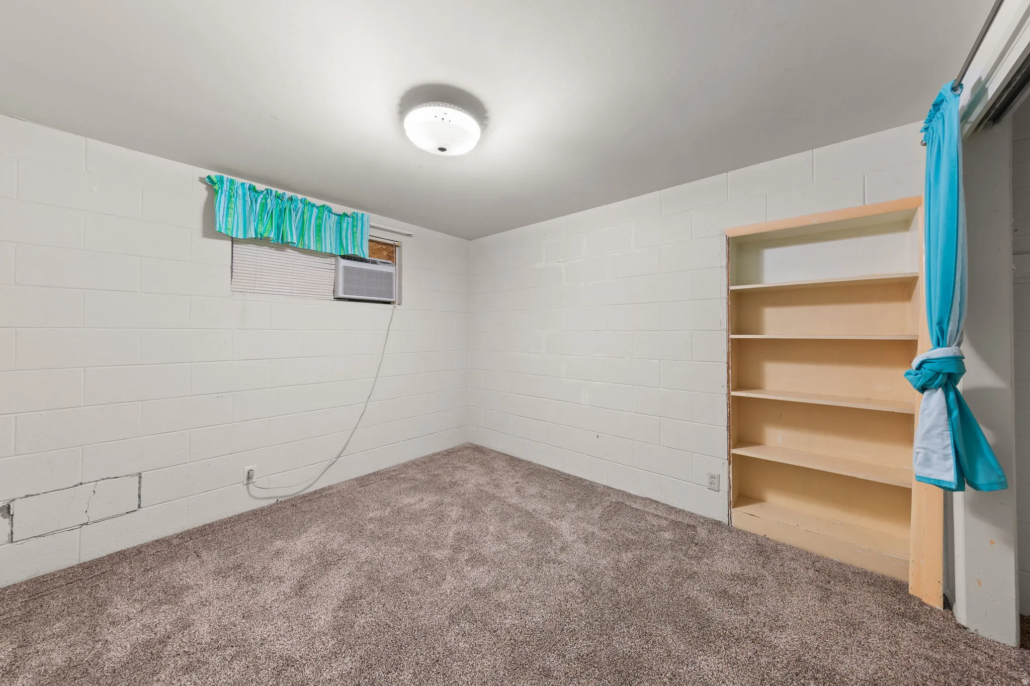 Carpeted room featuring white block walls