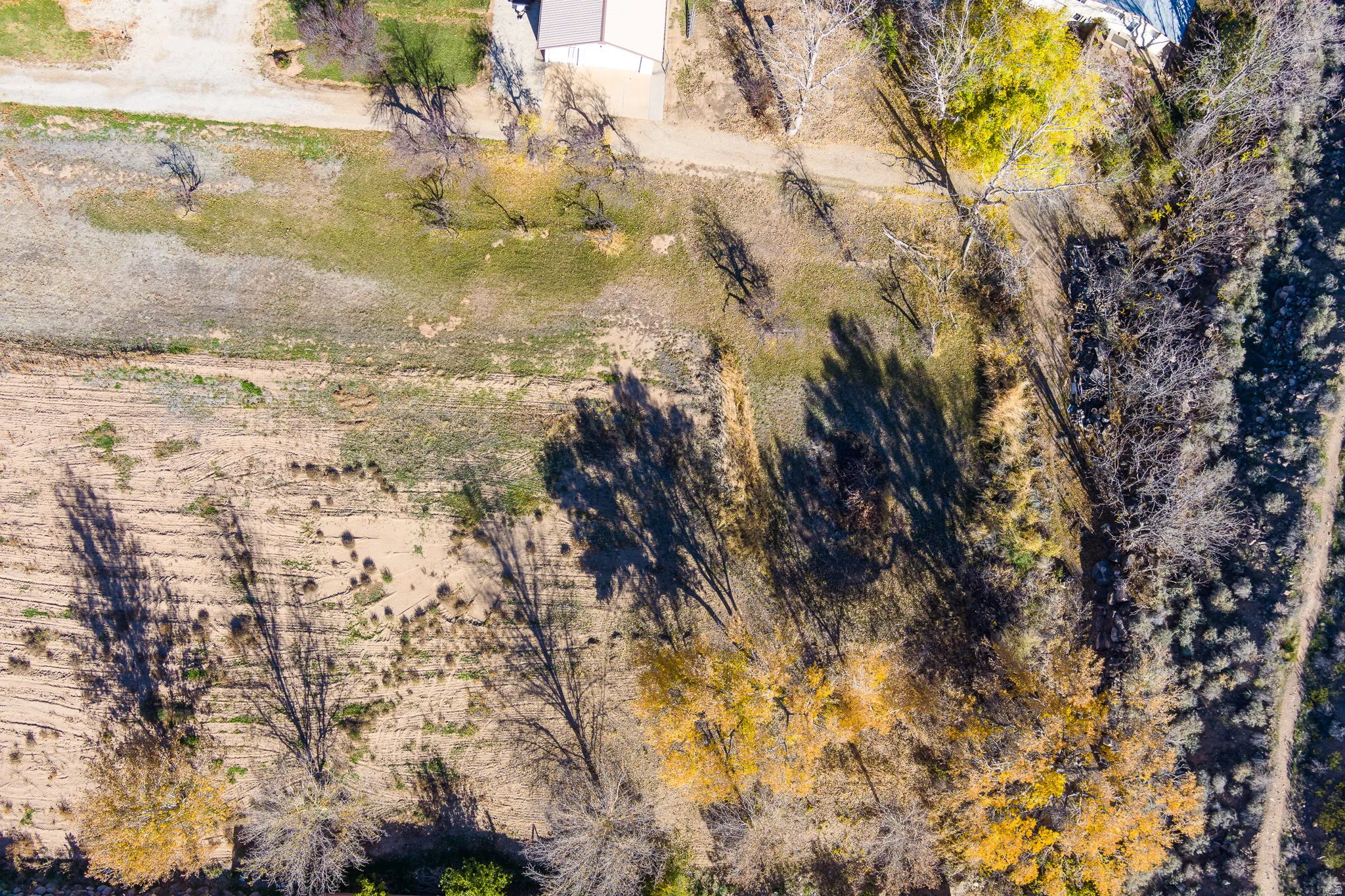 Expansive aerial view of a property featuring varied terrain, including areas of green ground cover and drier, lighter-colored ground