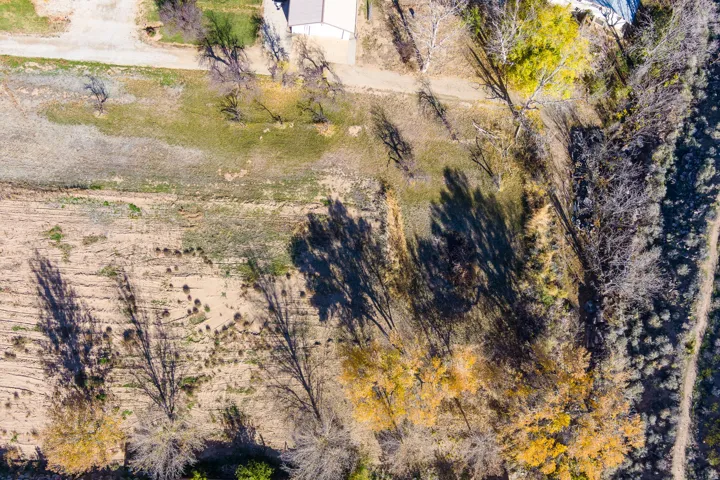 Expansive aerial view of a property featuring varied terrain, including areas of green ground cover and drier, lighter-colored ground