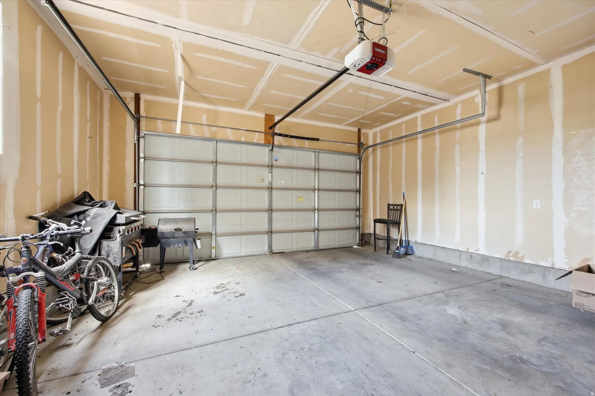 Spacious garage featuring a concrete floor, overhead door, and automatic garage door opener