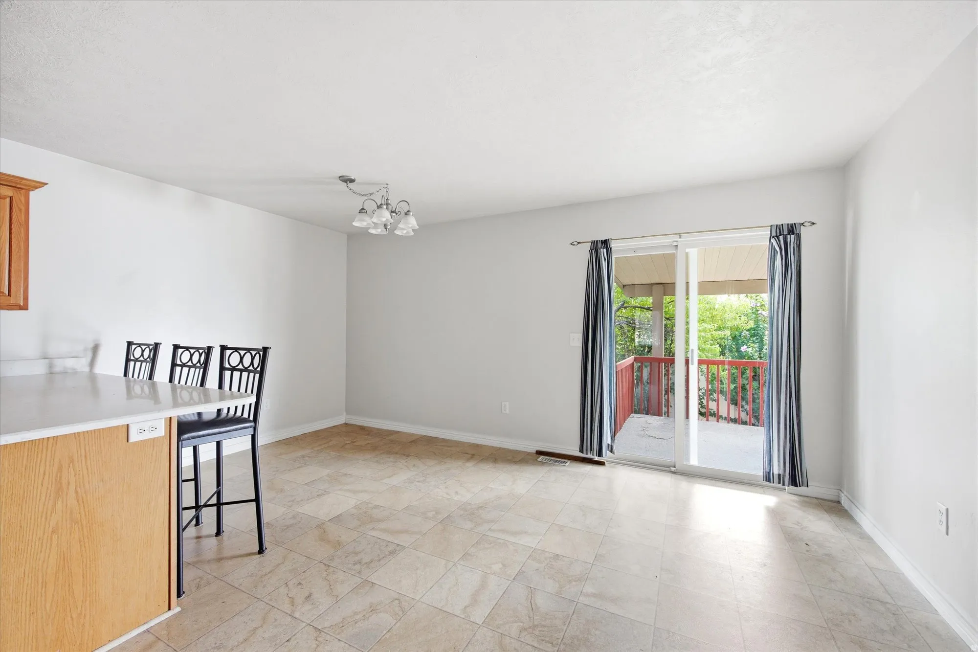 Dining area featuring tile flooring, a multi-light fixture, and sliding glass doors opening to a wood-railed balcony
