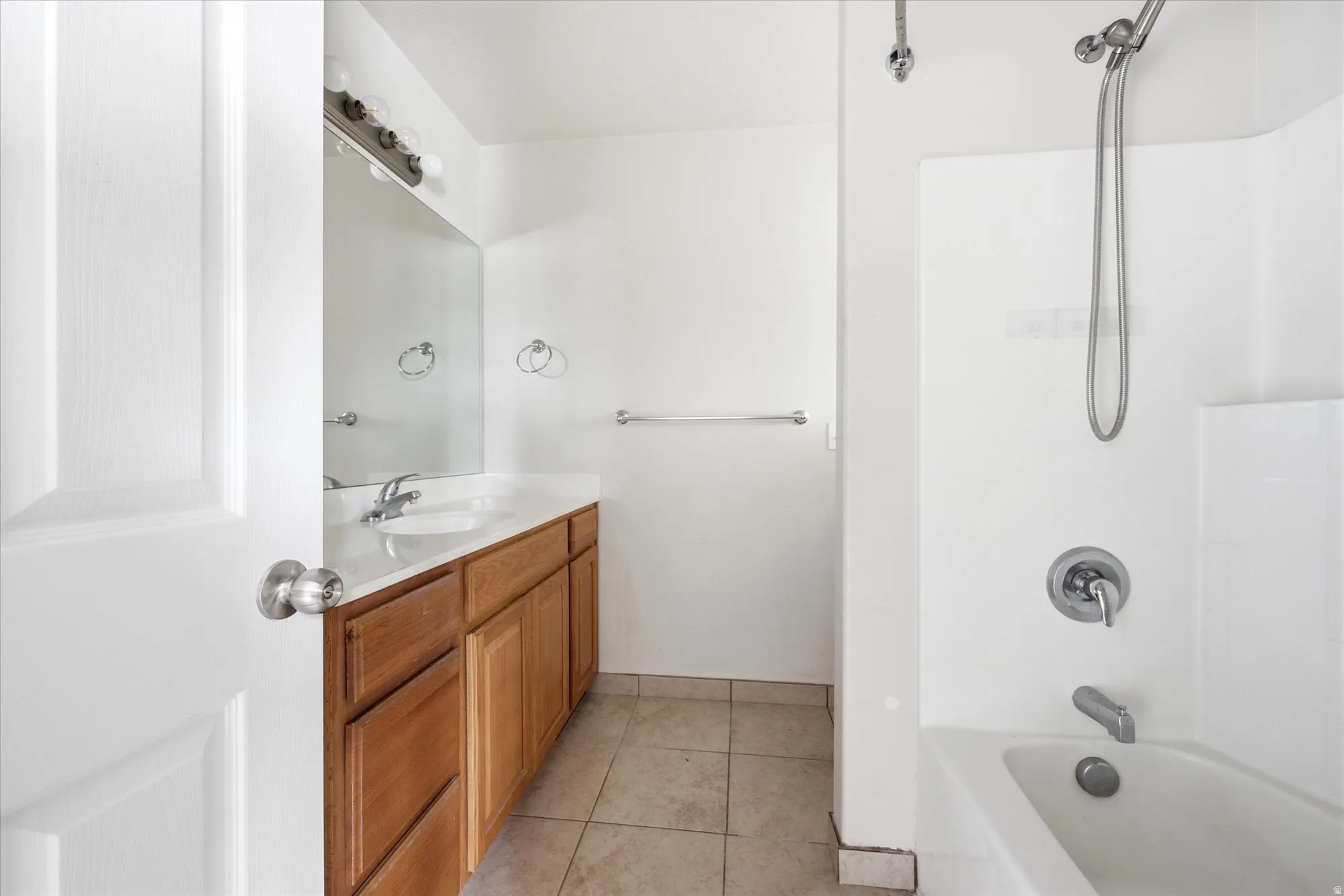 Bathroom featuring a wood-finish vanity with a white countertop, an integrated sink, and a large wall mirror