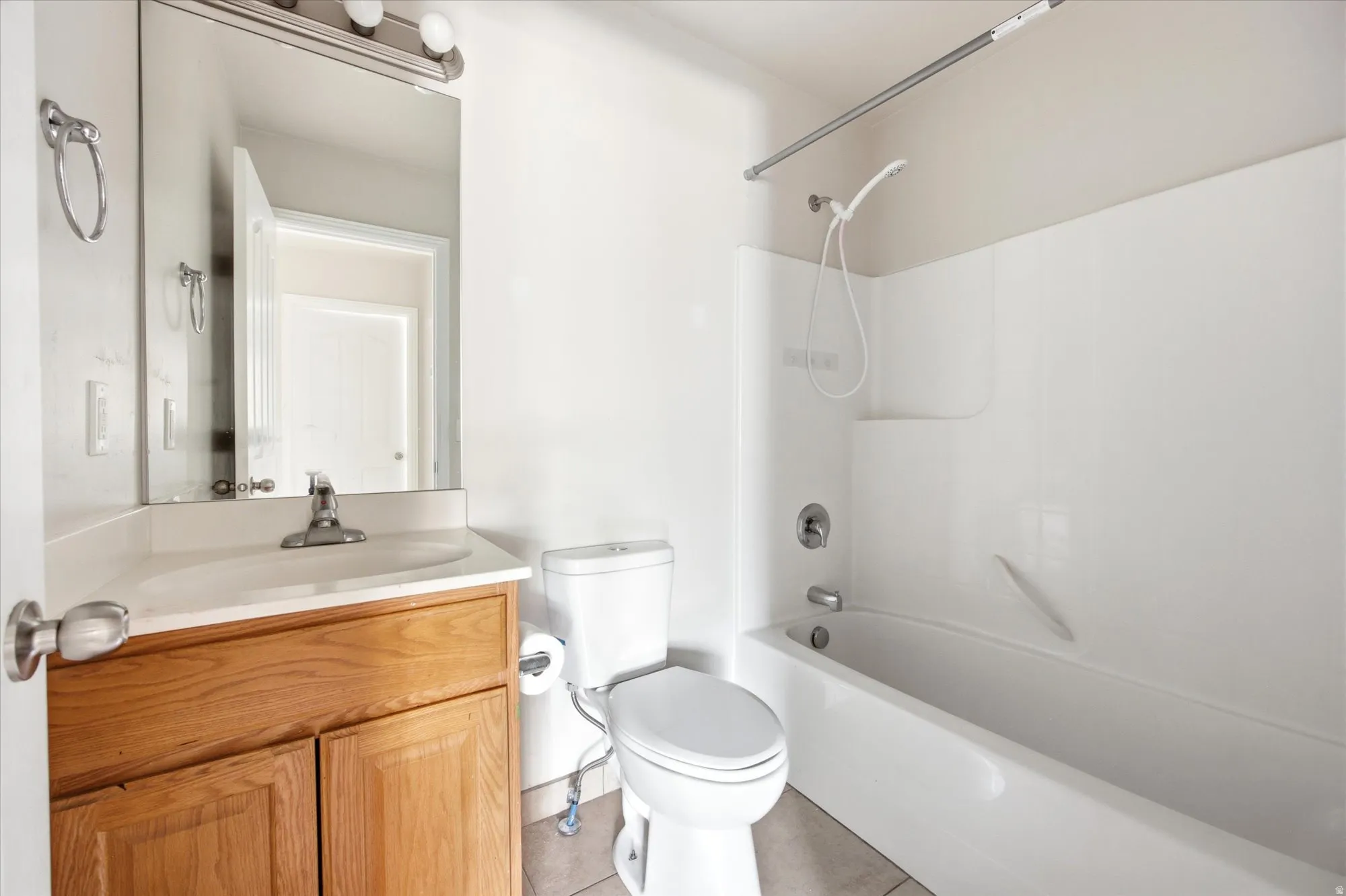 Bathroom with a single vanity featuring a wood-finish cabinet, integrated sink, and wall-mounted mirror