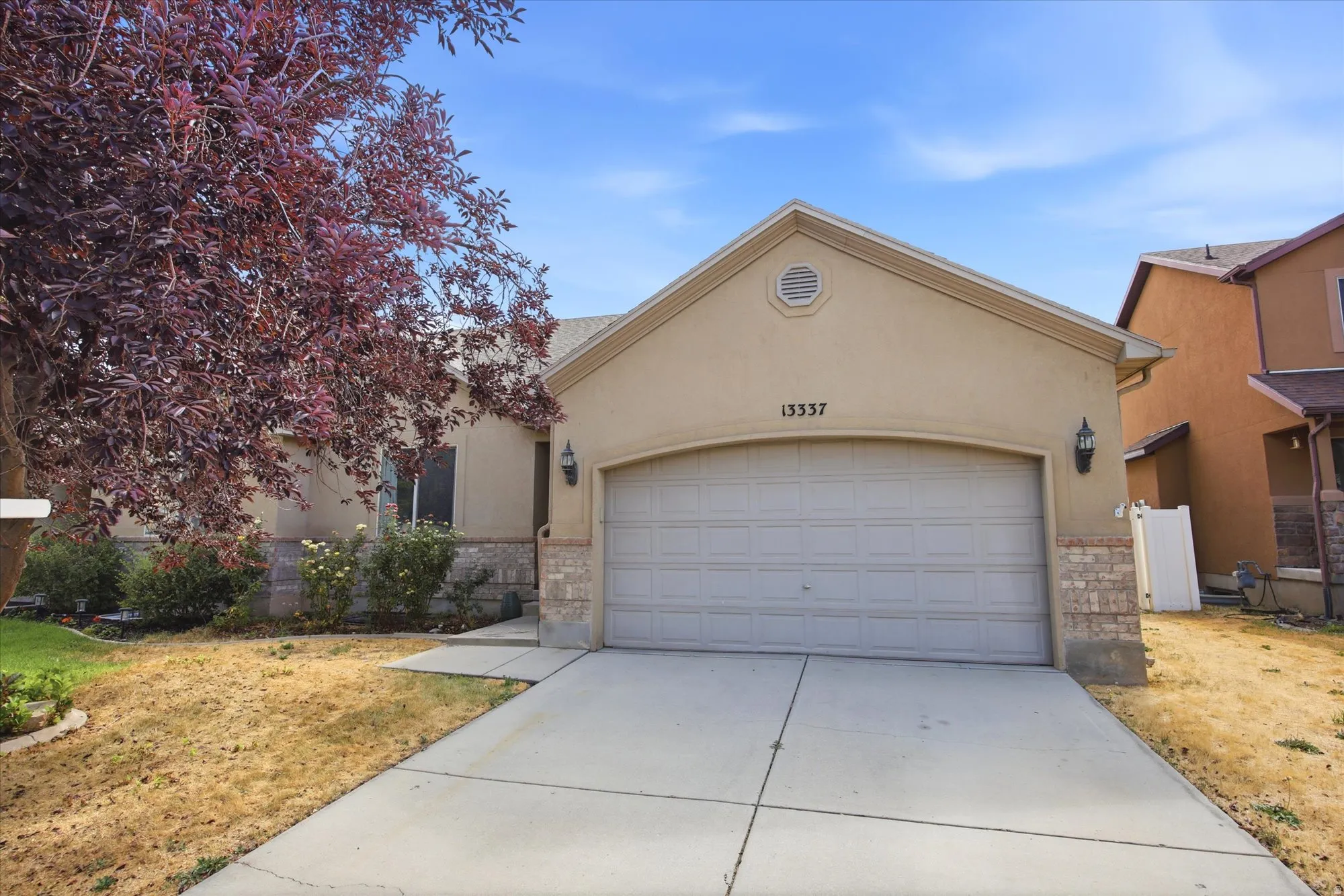 Stucco exterior featuring a prominent two-car garage with a panel door