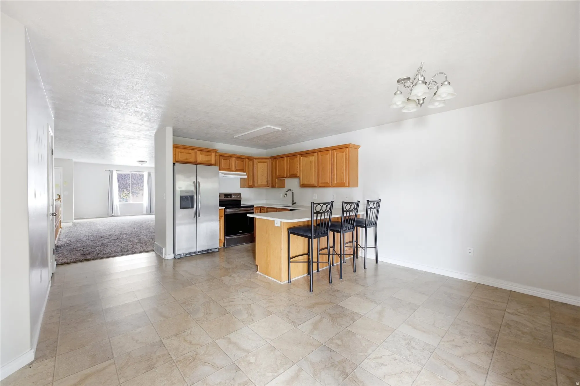 Kitchen featuring wood cabinetry, stainless steel refrigerator, and a breakfast bar with seating for three