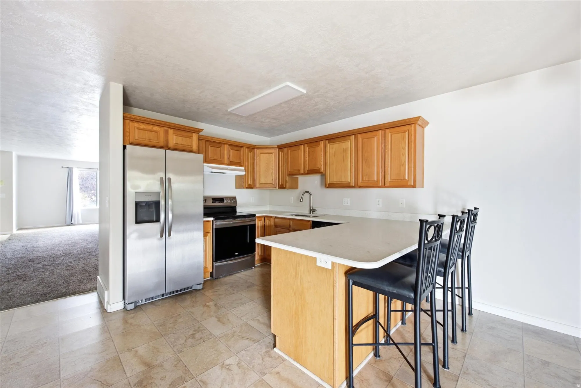 Kitchen featuring light-tone cabinetry, stainless steel appliances, and a peninsula with a light-colored countertop