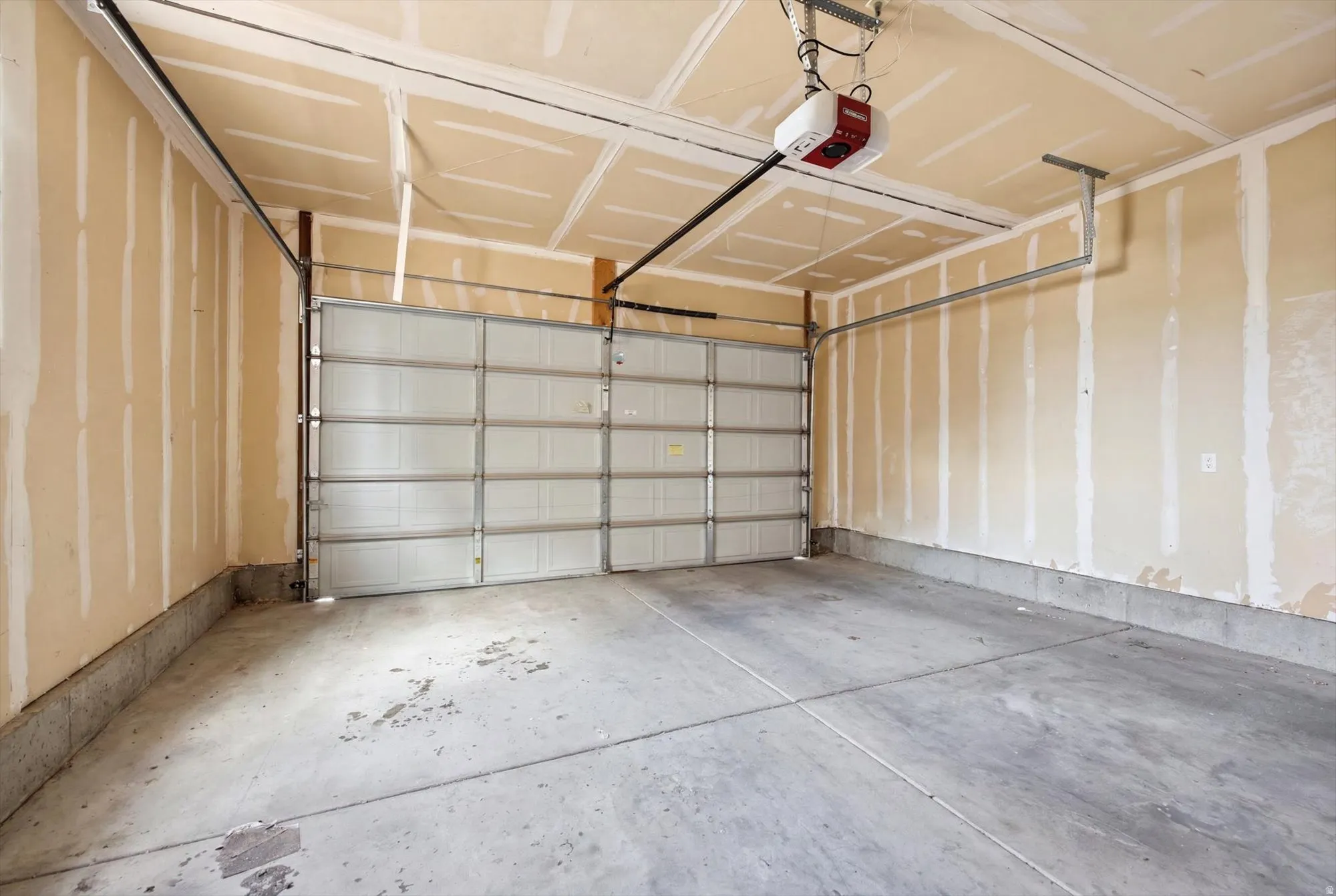 Two-car garage featuring a concrete floor, an overhead automatic garage door opener, and a panel-style garage door