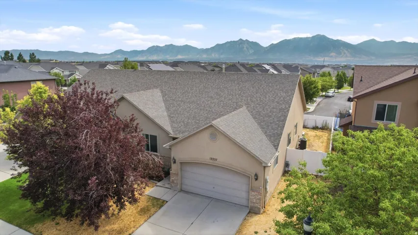 Contemporary stucco exterior with an attached garage, a mature tree, and mountain scenery