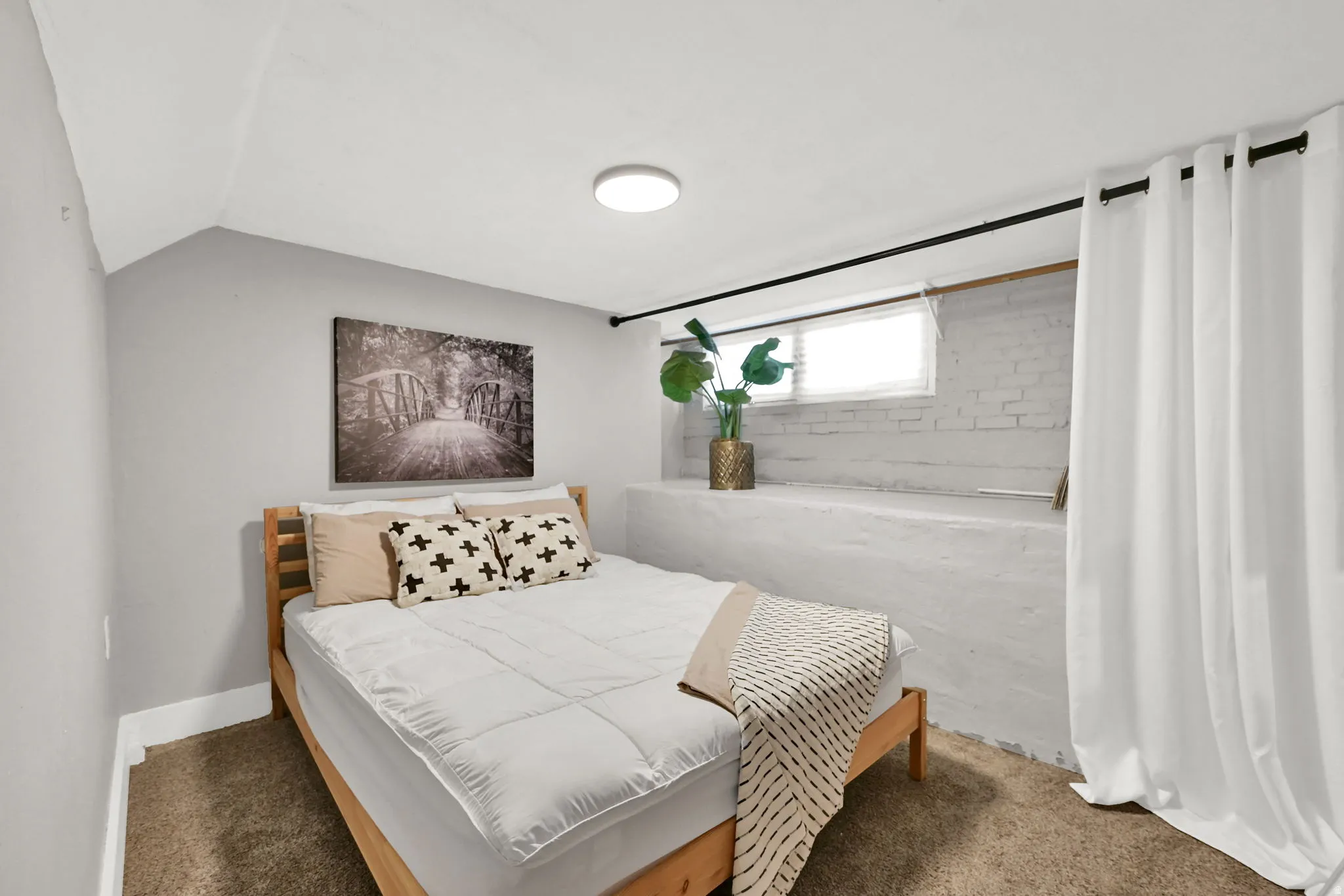 Bedroom featuring light gray walls, a window with blinds, and white painted brickwork