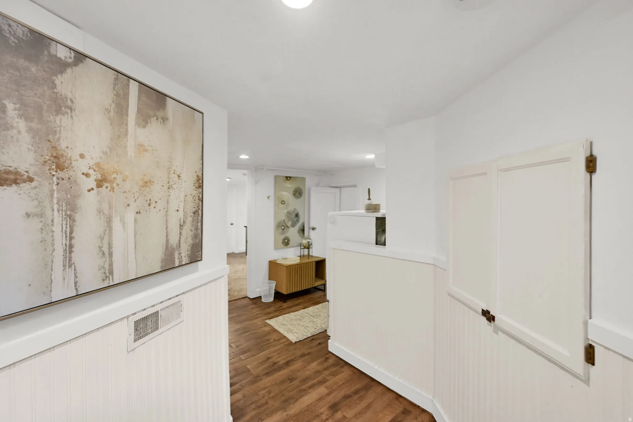 Hallway featuring wood-finish flooring and white beadboard wainscoting