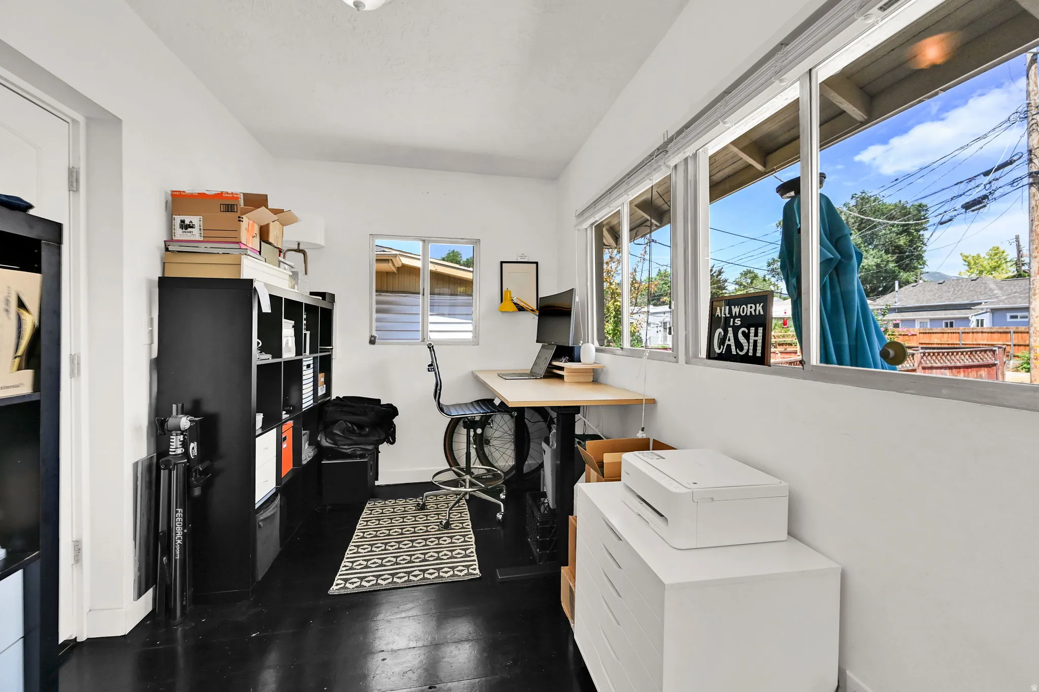 Naturally lit room featuring a series of large windows, white walls, and dark wood-finish flooring