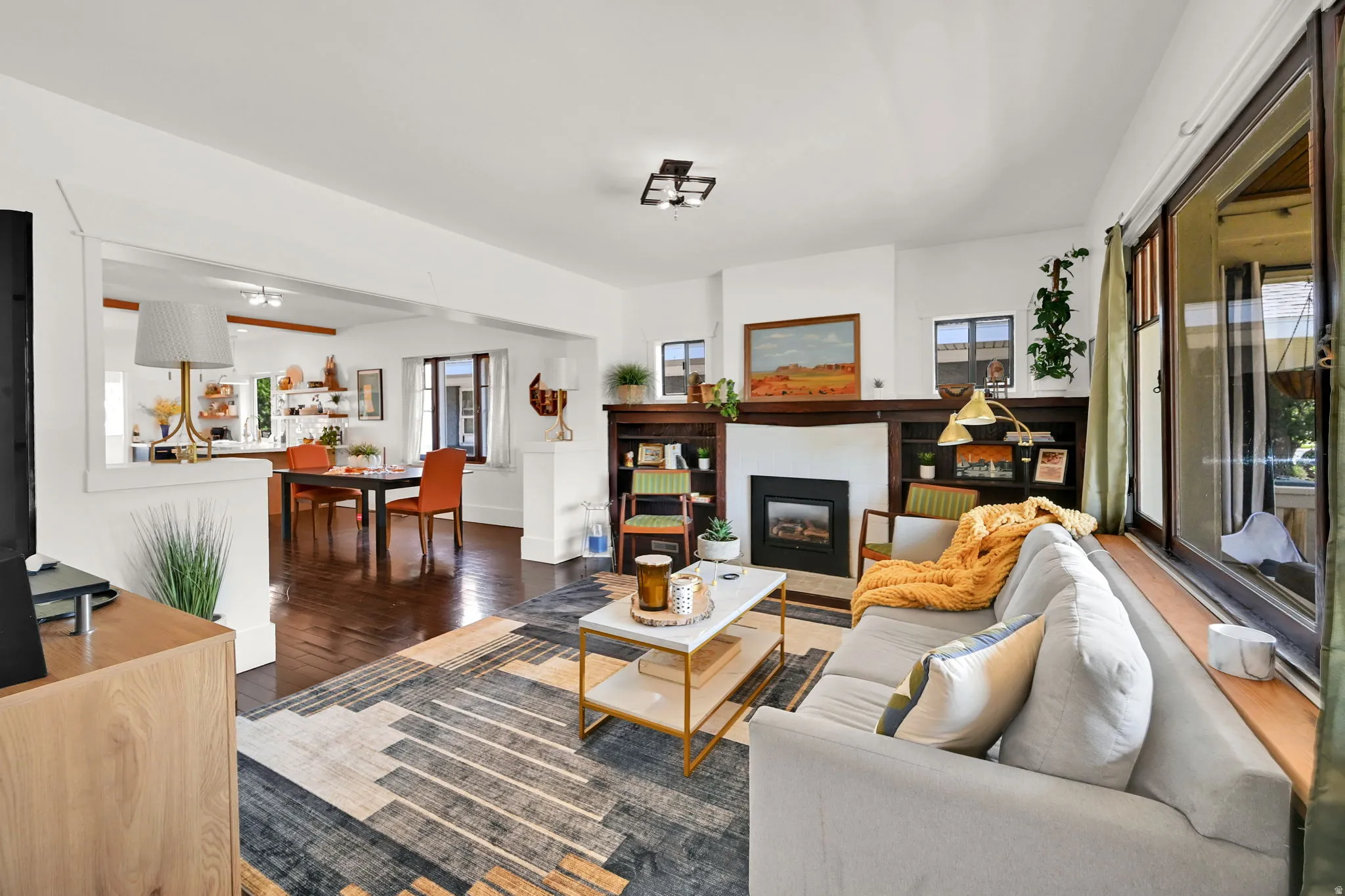 Living area featuring wood-finish flooring, a built-in fireplace with a dark wood surround, integrated shelving, and large windows