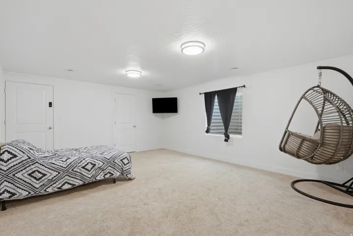 Spacious room with light-colored carpeting, two panel doors, and a window with blinds