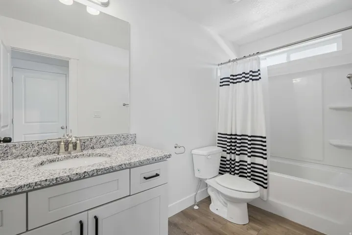 Bathroom featuring a white vanity with a granite countertop, undermount sink, and brushed nickel faucet
