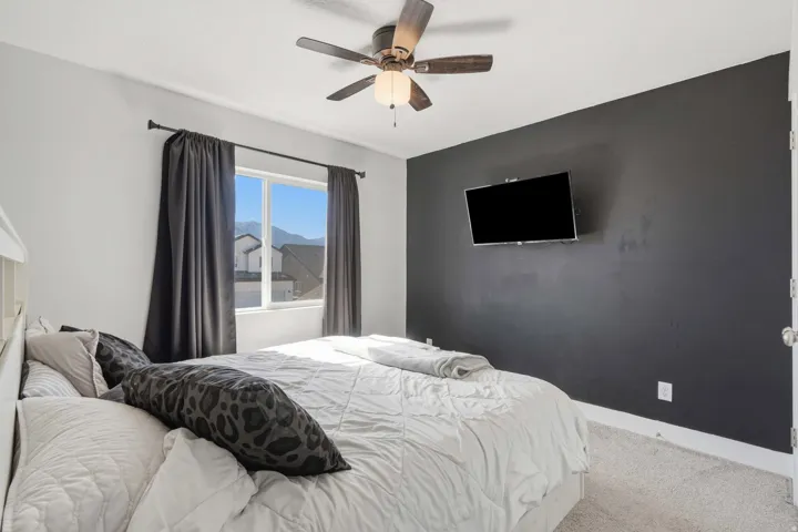 Carpeted room featuring a ceiling fan with integrated lighting, a window with mountain scenery, and a dark accent wall