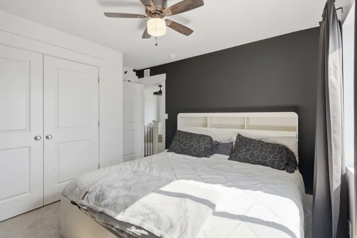 Bedroom featuring a dark accent wall, white trim, and a ceiling fan with integrated lighting