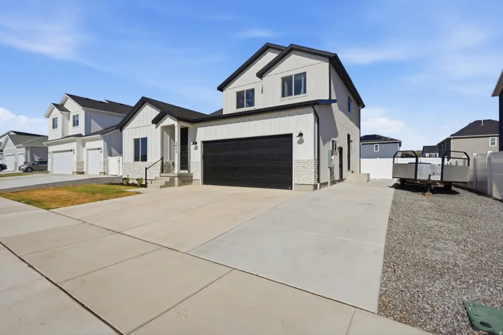 Contemporary two-story residence featuring a black garage door and white vertical siding