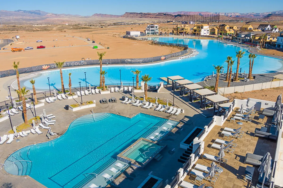 Expansive outdoor amenity area featuring a large lagoon-style pool, a secondary swimming pool with a hot tub, and multiple shaded lounging structures