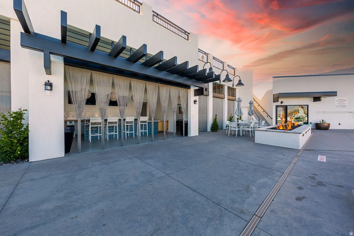 Expansive outdoor patio featuring a pergola-covered dining area with privacy curtains, a built-in fire pit, and an additional open-air dining space