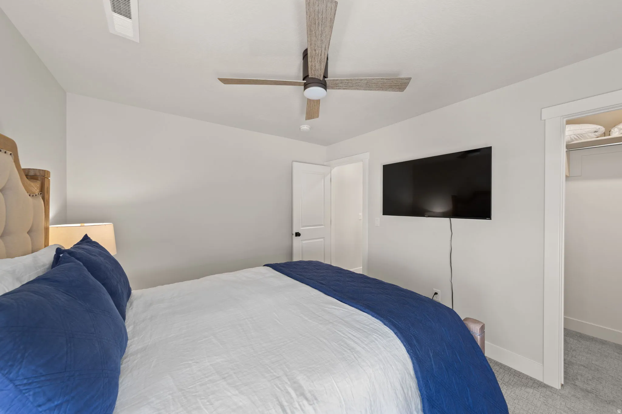 Bedroom featuring light gray walls, a ceiling fan with wood-look blades, and light gray carpeting