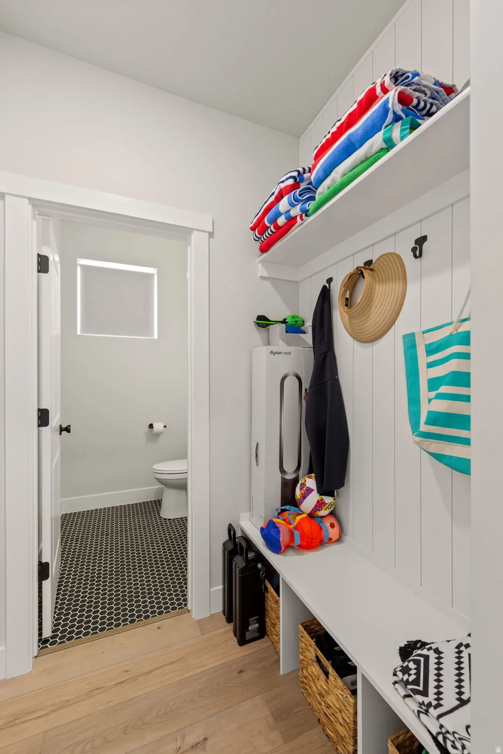 Built-in storage bench with overhead shelving and wall hooks