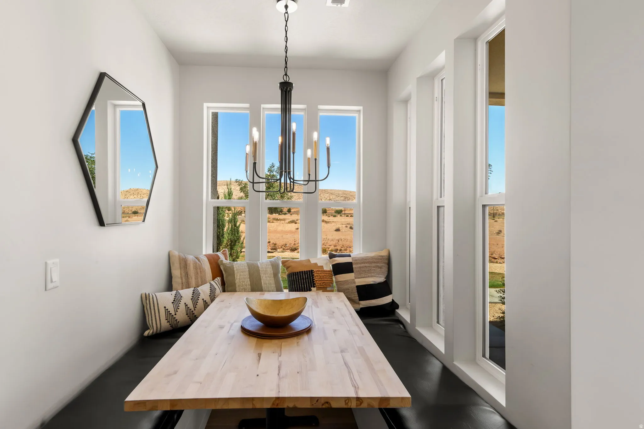 Integrated dining nook with a wood-finish table, built-in bench seating, and an overhead chandelier