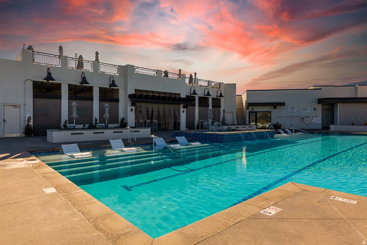 Resort-style pool area featuring an expansive swimming pool with submerged lounge seating
