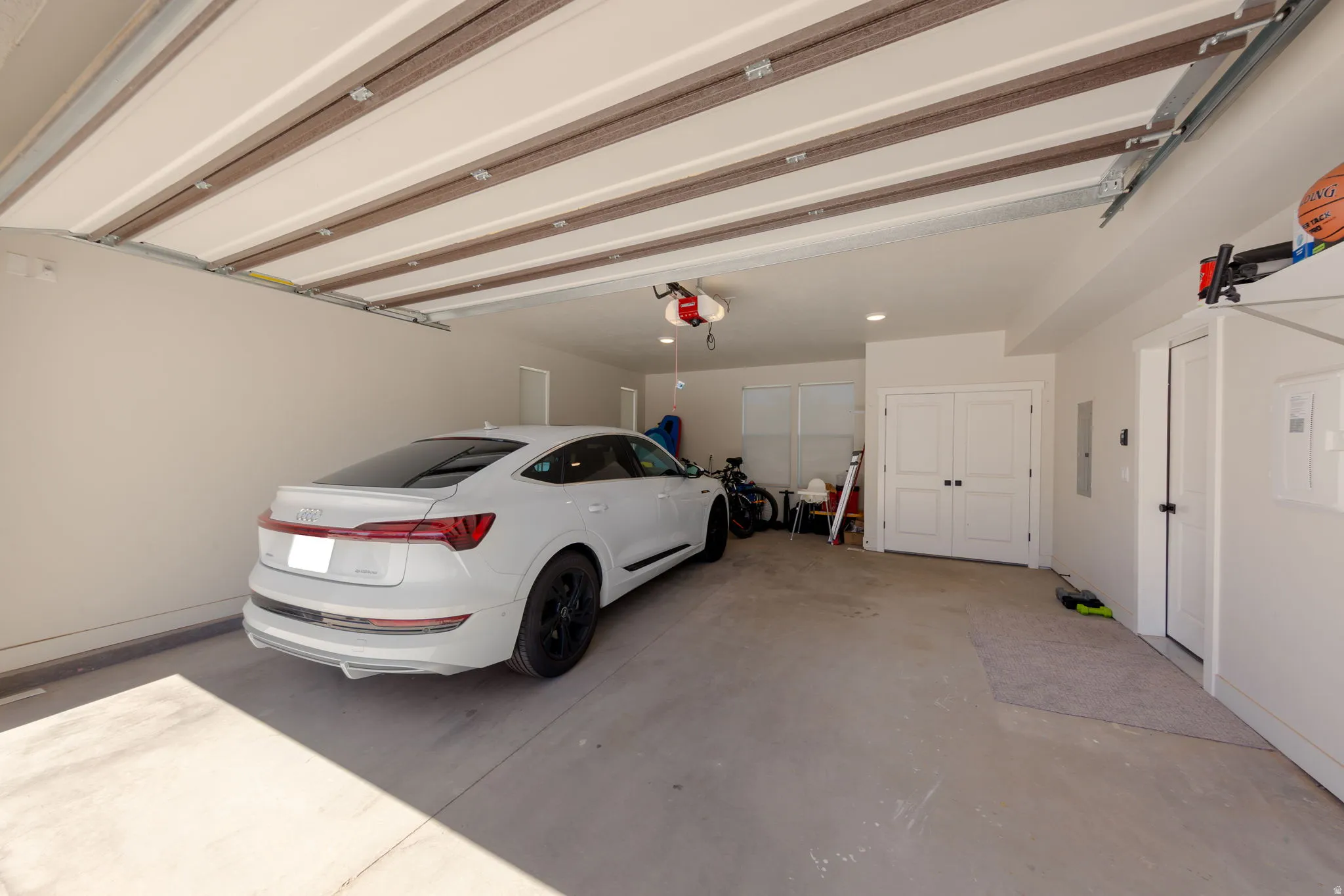 Spacious garage with light grey concrete flooring, white walls, and a white paneled overhead door