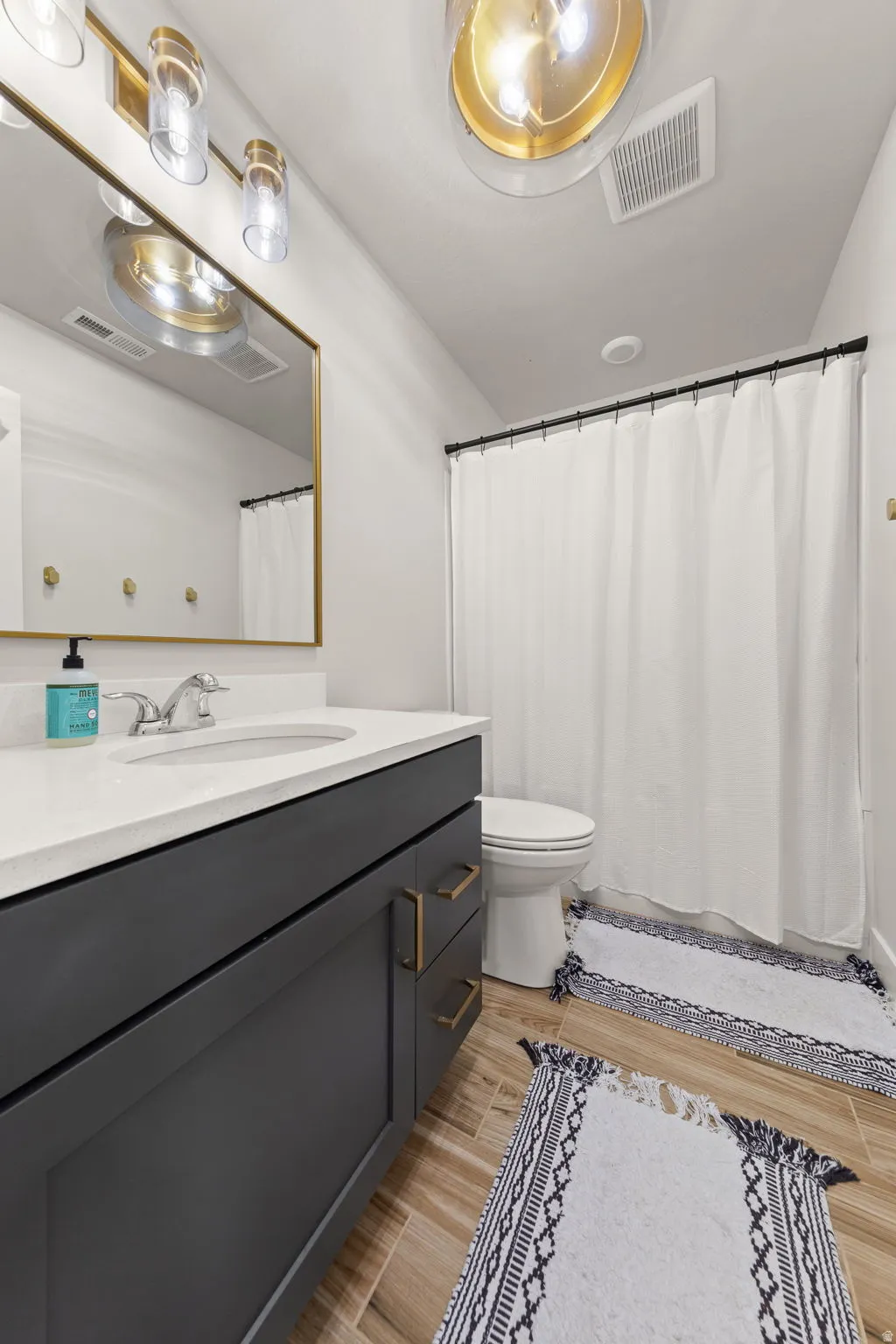 Bathroom featuring a gray vanity with gold-tone hardware, white countertop, and under-mount sink