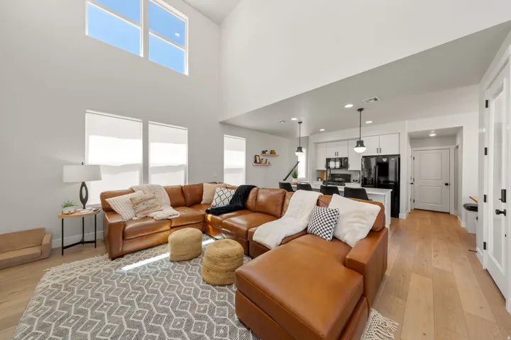 Double-height living area featuring high ceilings, upper transom windows, recessed lighting, and wood-finish flooring