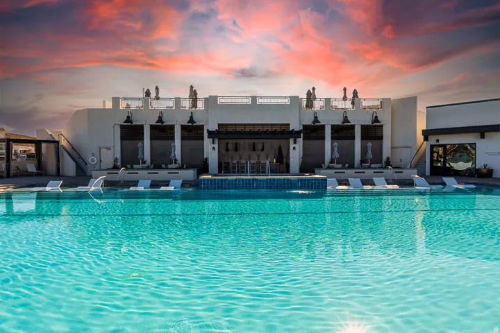 Resort-style pool with integrated loungers and water features, set against a multi-level building