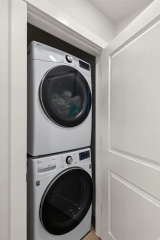 Stackable washer and dryer units in a dedicated closet, featuring white panel doors and light wood-finish flooring