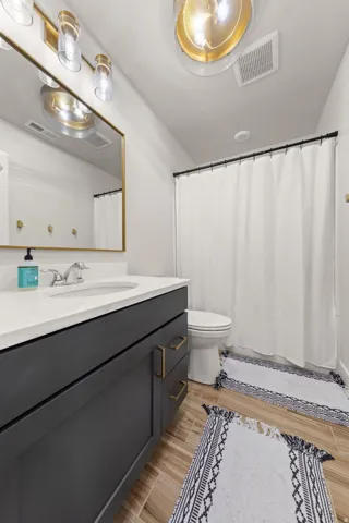 Bathroom featuring a gray vanity with gold-tone hardware, white countertop, and under-mount sink