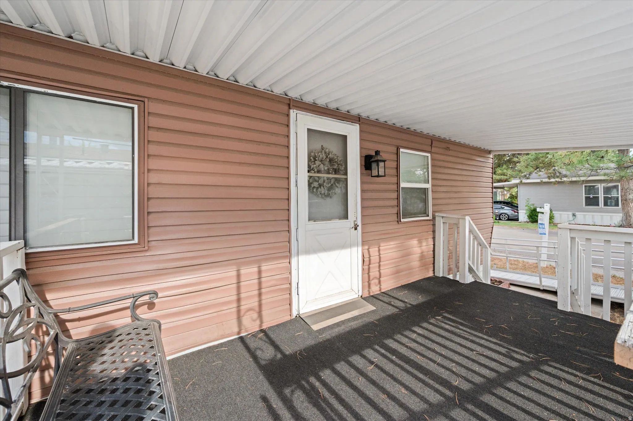 Covered front porch featuring textured brown siding and a white entry door