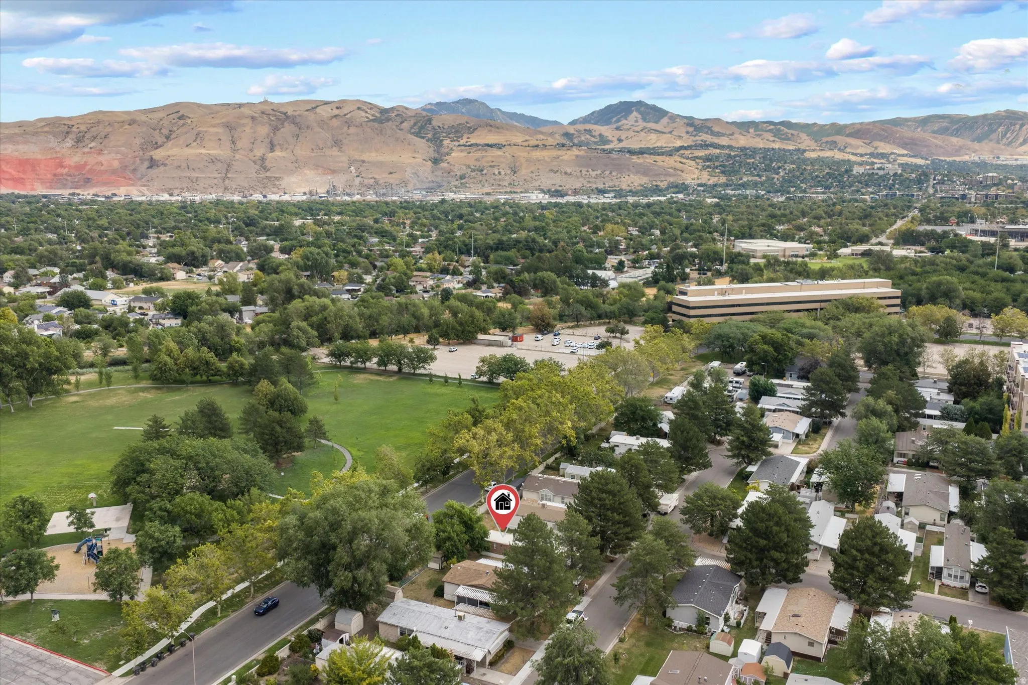 Aerial perspective highlighting the property within a residential area featuring mature trees and mountain backdrops