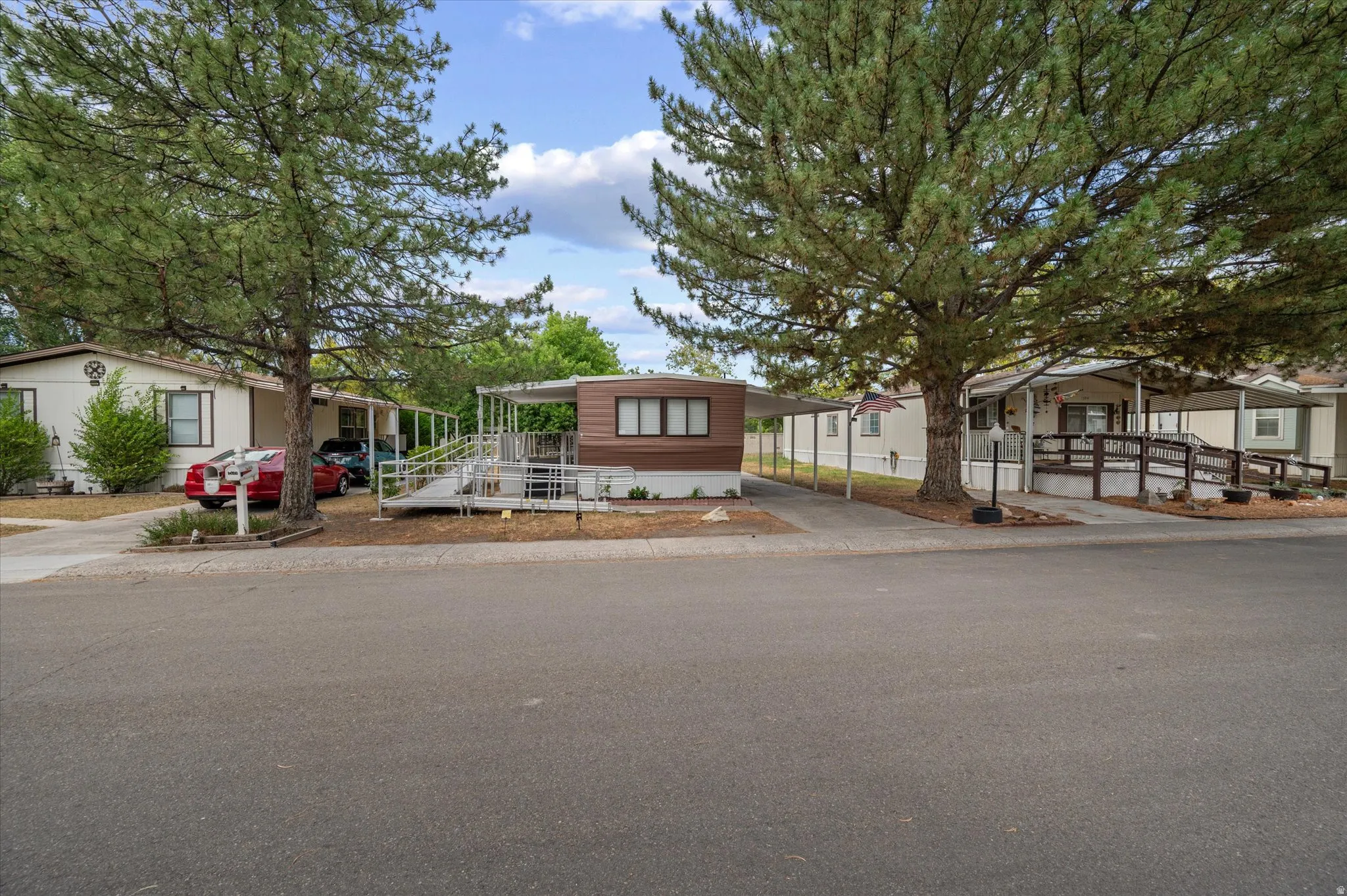 Property exterior featuring a brown and cream facade, a covered carport, and an extended access ramp