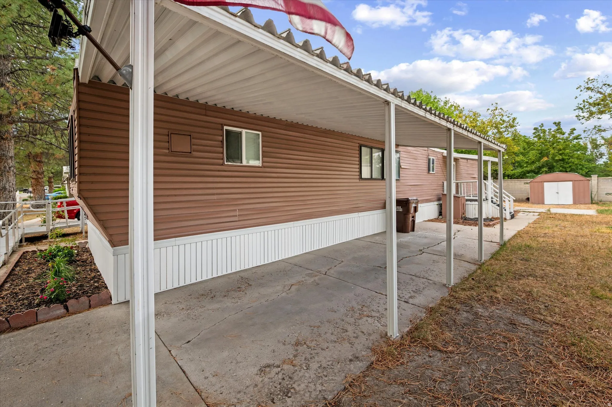 Covered carport featuring a concrete pad and metal support posts