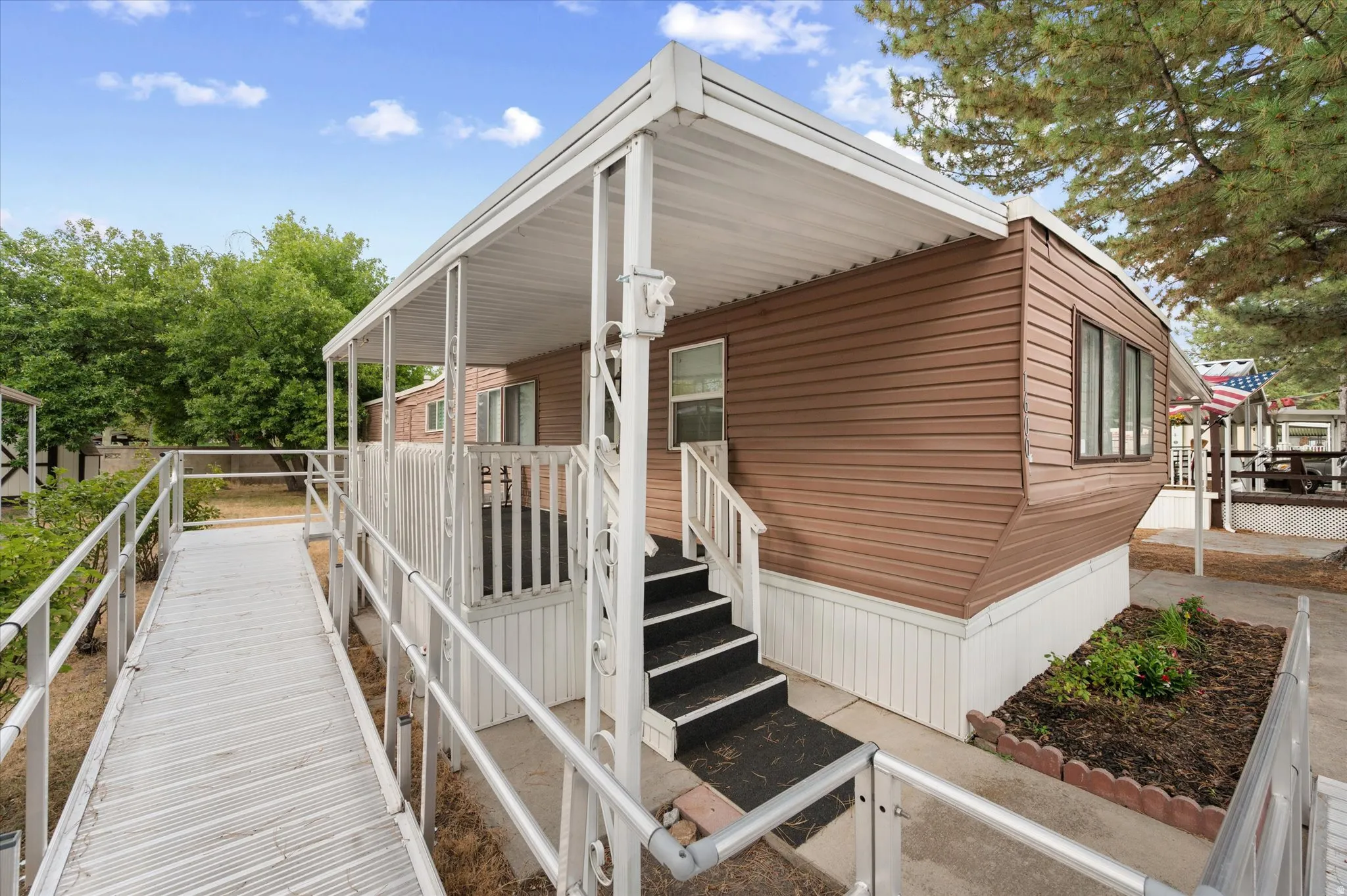 Exterior features brown siding, white skirting, and a covered porch