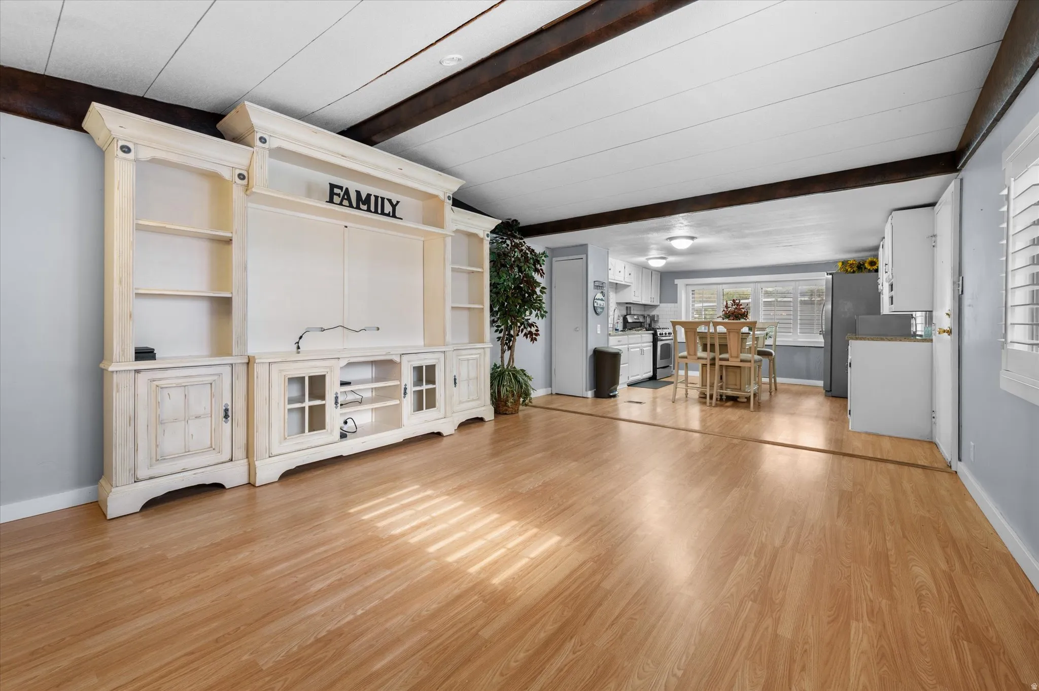 Spacious living area featuring wood-finish flooring and exposed ceiling beams