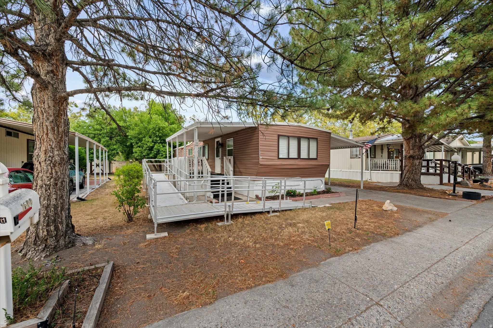Brown siding exterior with white trim, featuring a covered porch and accessible ramp entry