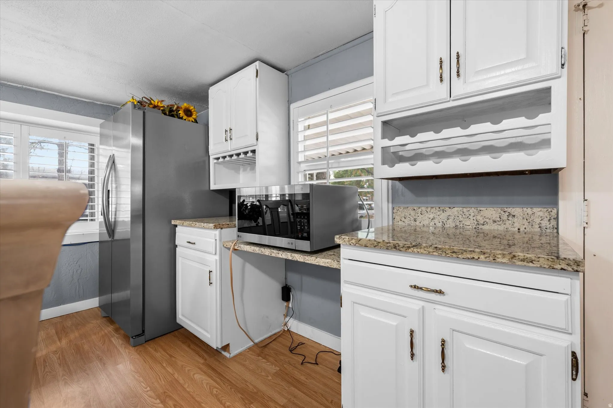 Kitchen featuring white cabinetry, granite-finish countertops, wood-finish flooring, and a built-in wine rack