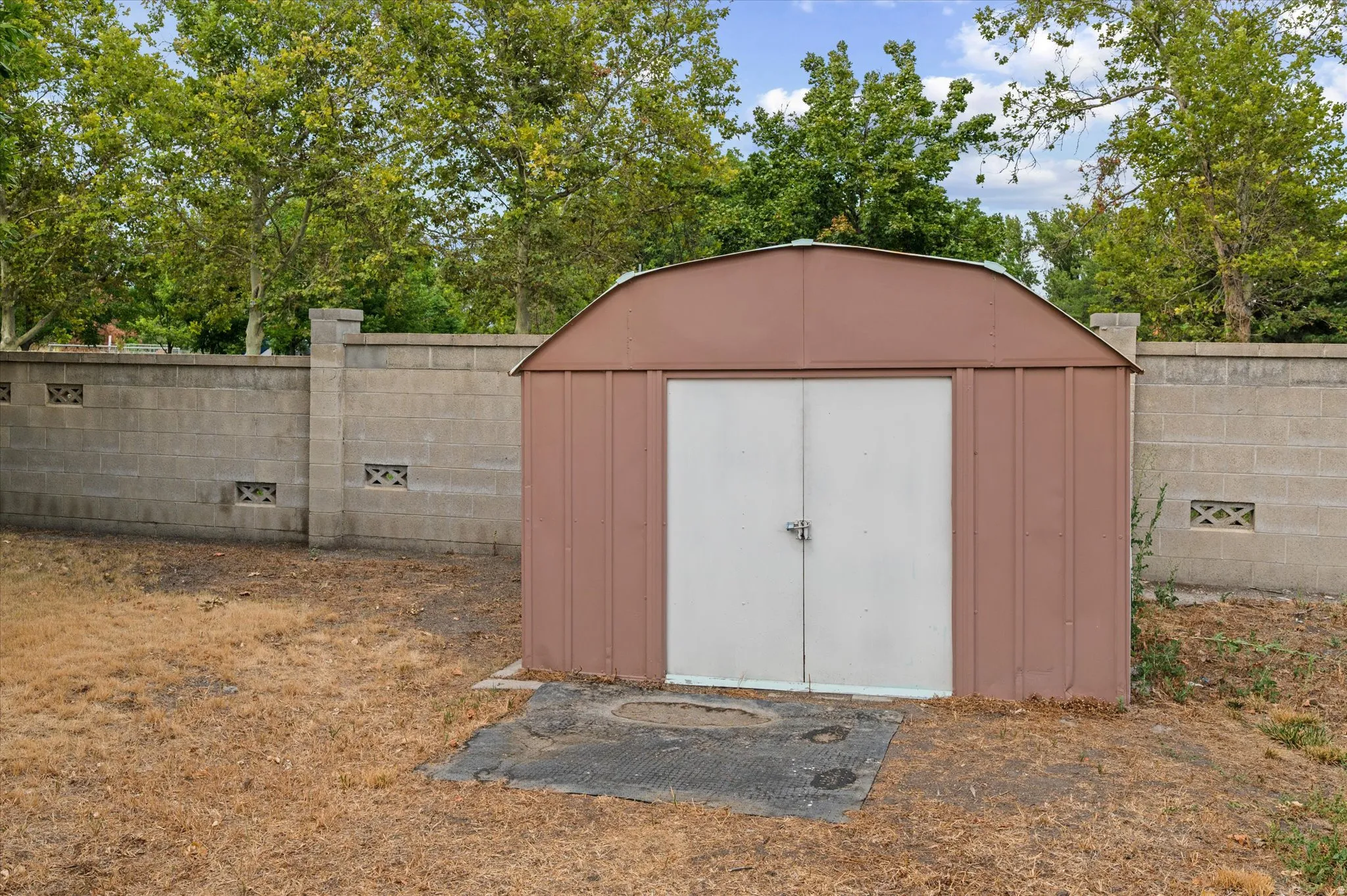 Metal storage shed with double doors, set on a concrete pad