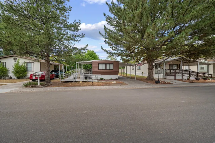 Property exterior featuring a brown and cream facade, a covered carport, and an extended access ramp
