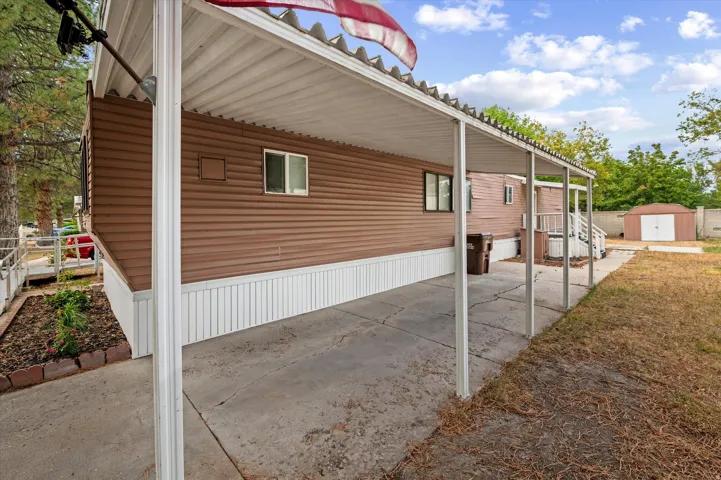 Covered carport featuring a concrete pad and metal support posts