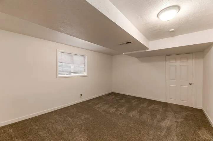Carpeted room with white walls, a white paneled door, and an overhead flush-mount light fixture