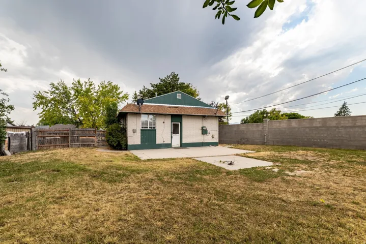 Rear exterior featuring a concrete patio, wood fence, and concrete block wall